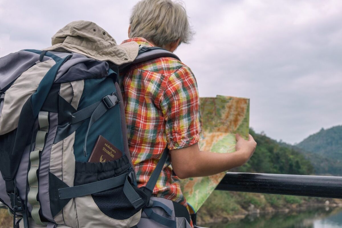 Offres A backpacker examining a map against a scenic outdoor landscape. Adventure awaits.