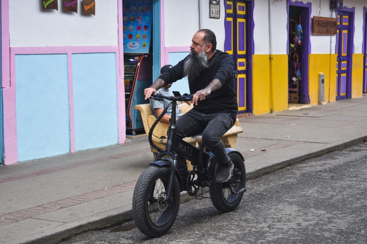A man rides an electric bike along a colorful street facade, capturing urban lifestyle.